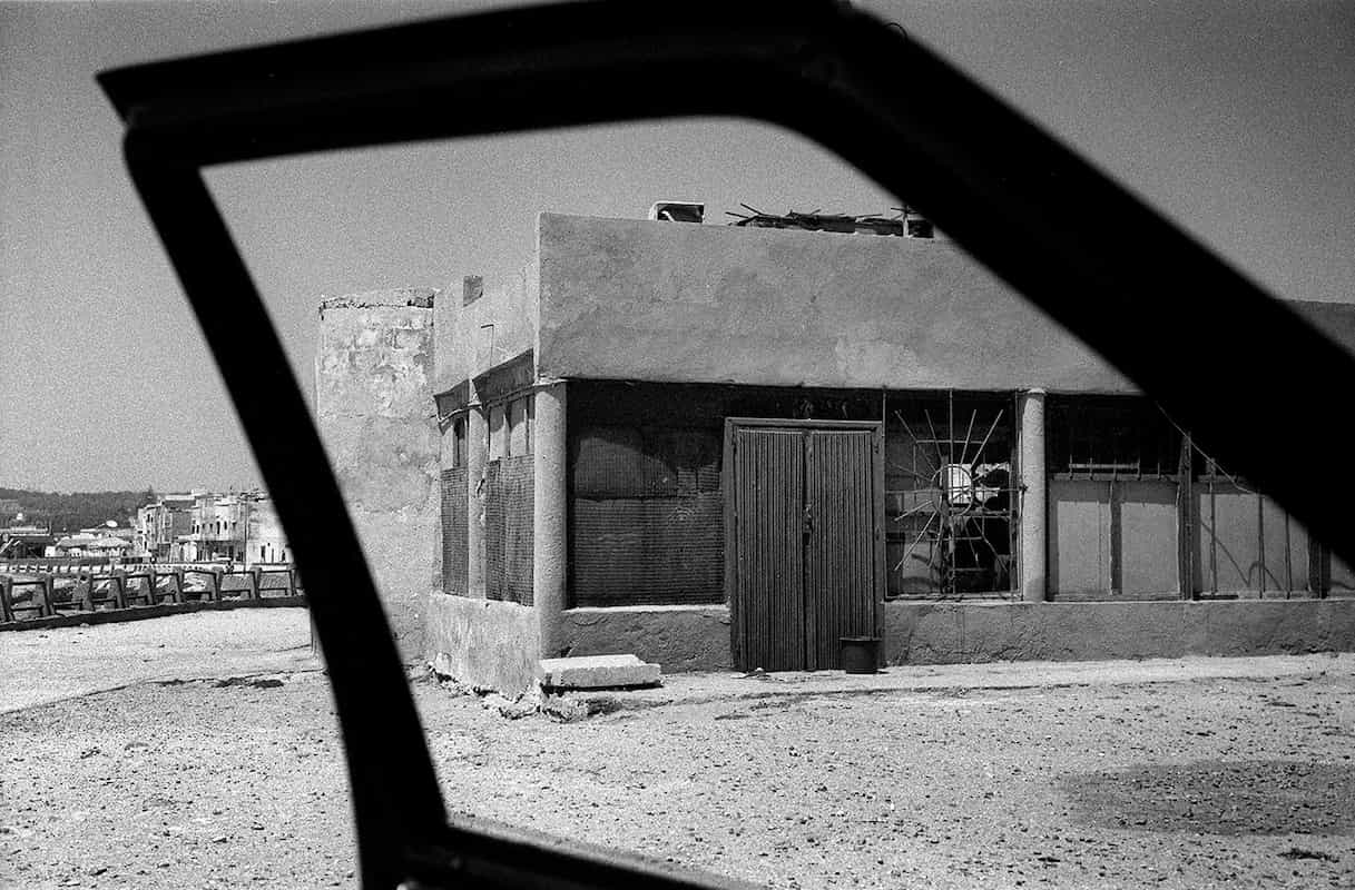 photographie noir et blanc d'une une portière de voiture donnant sur un bâtiment © francois nussbaumer